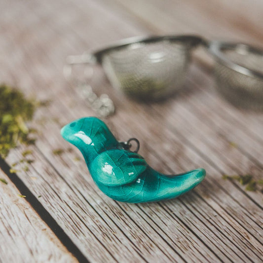 Tea infuser with ceramic light blue bird hanging from the chain.