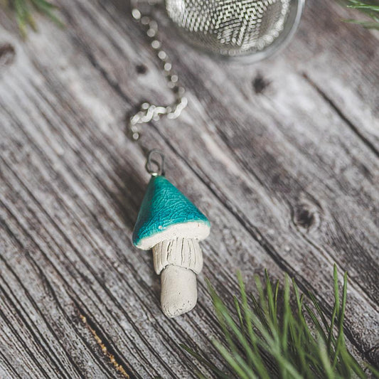 Tea infuser with ceramic light blue mushroom hanging from the chain.