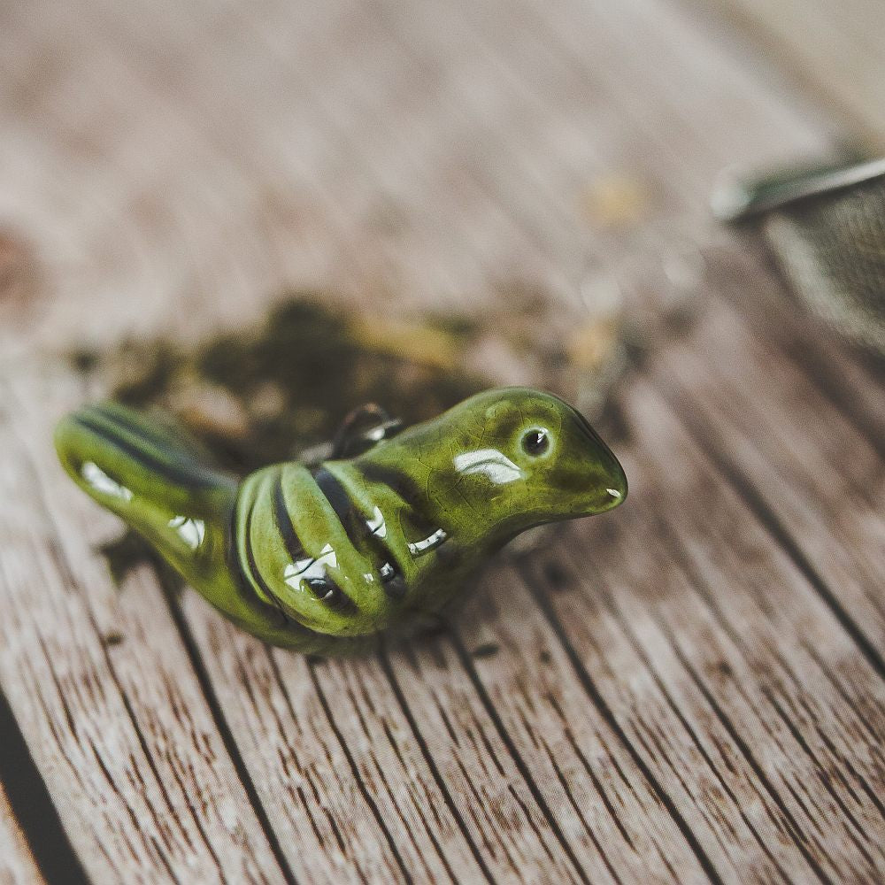 Tea infuser with ceramic moss green bird hanging from the chain.