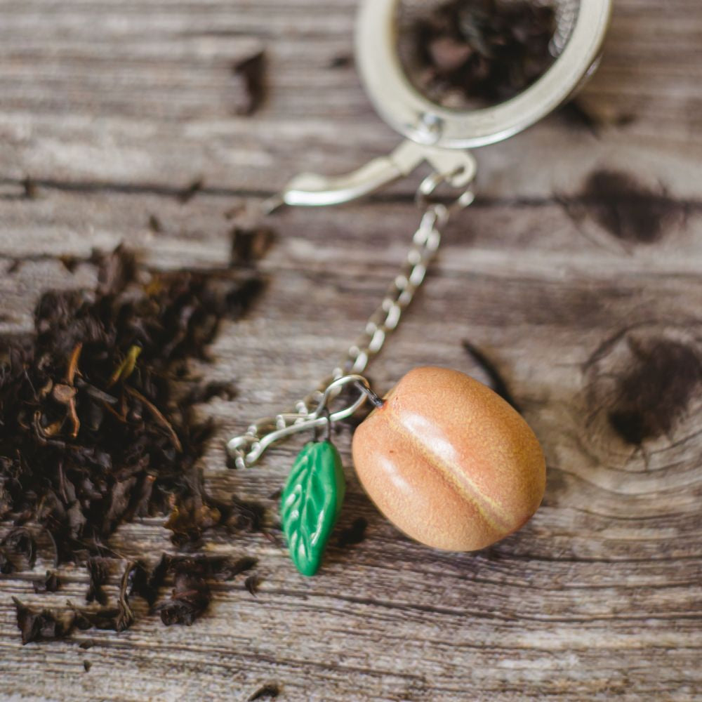 tea infuser with ceramic peach hanging from the chain