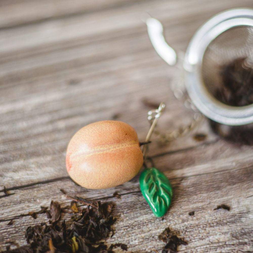 tea infuser with ceramic peach hanging from the chain
