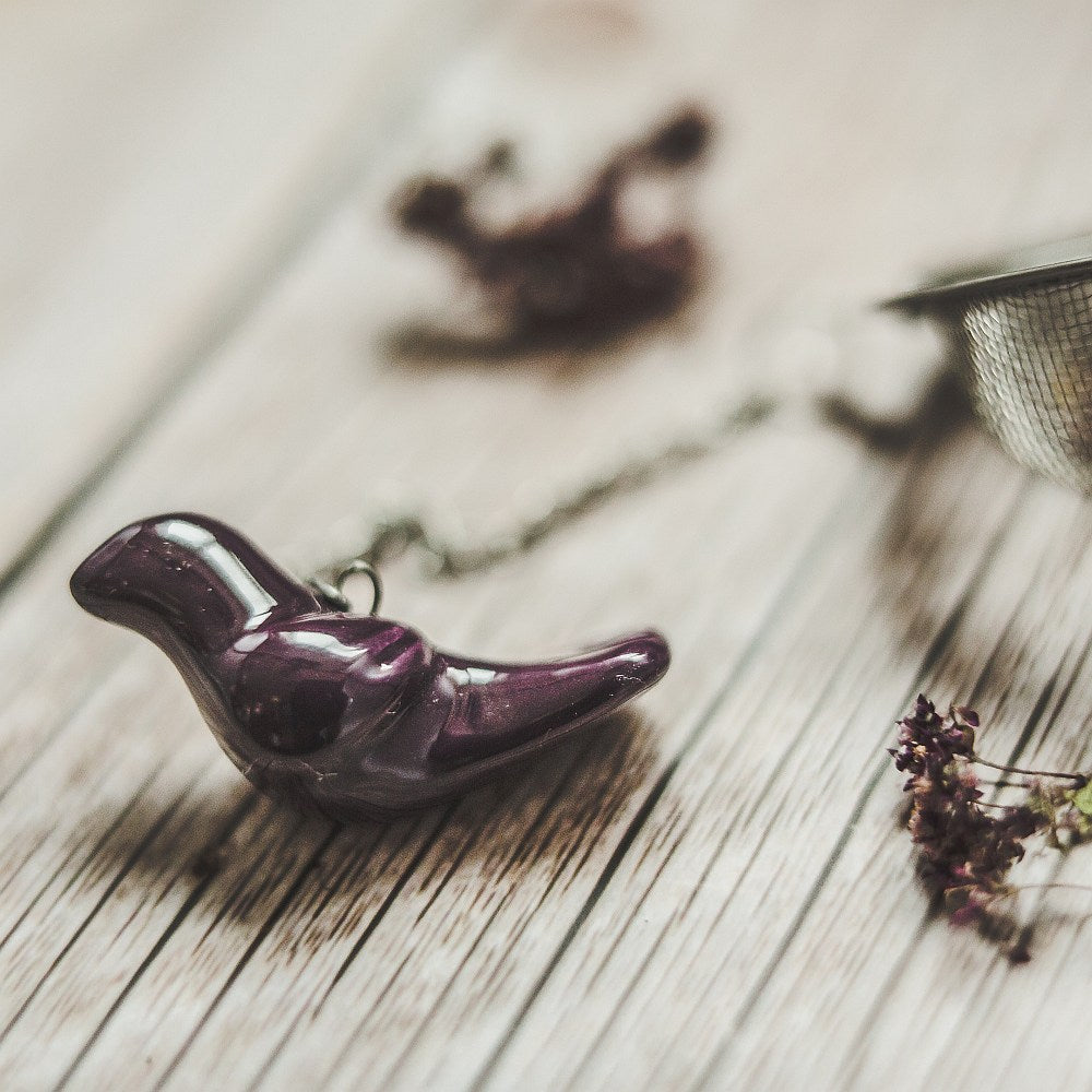 Tea infuser with ceramic purple bird hanging from the chain.