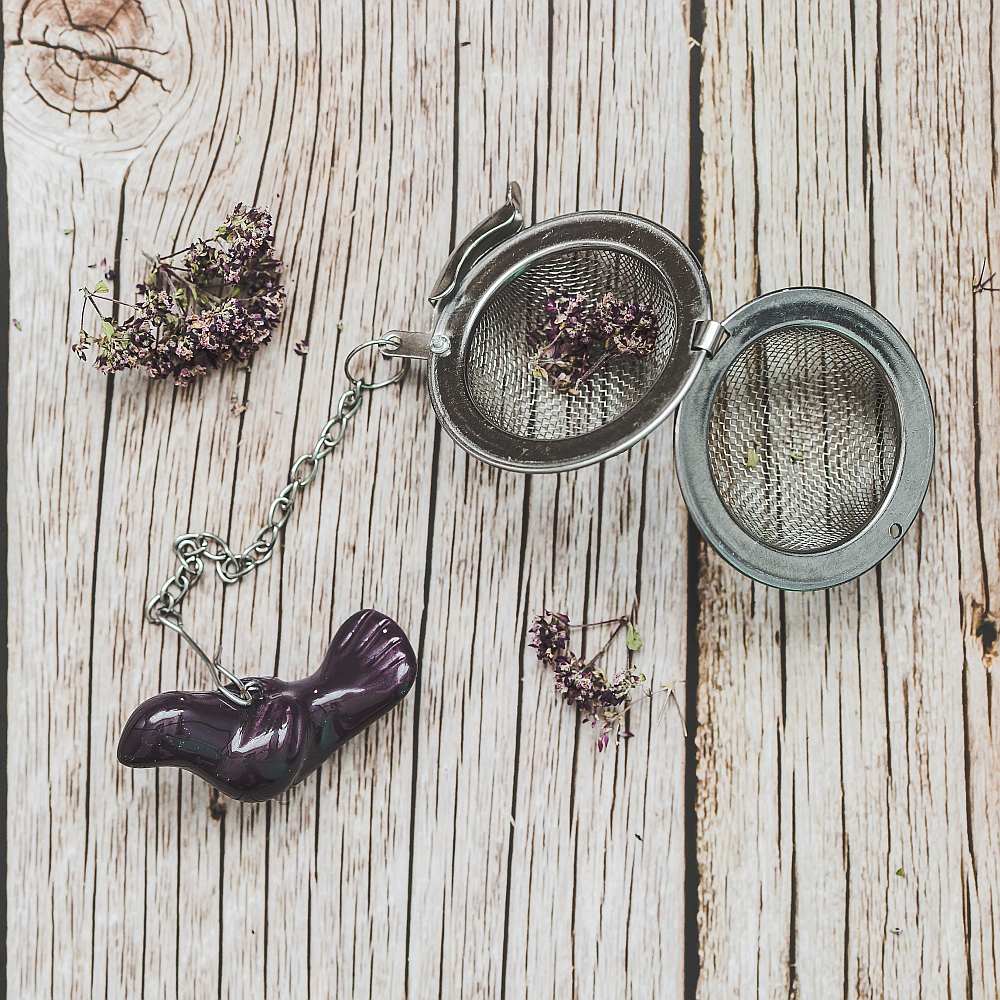Tea infuser with ceramic purple bird hanging from the chain.