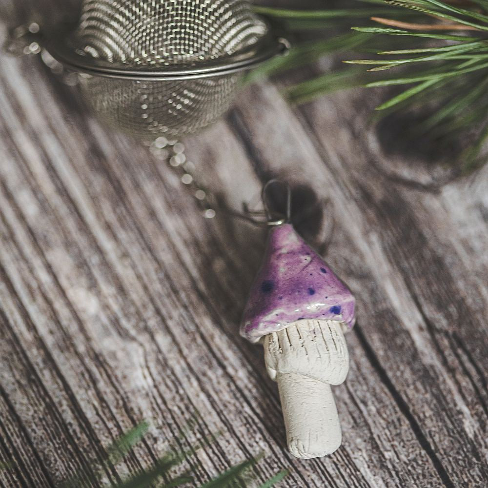 Tea infuser with ceramic purple mushroom hanging from the chain.