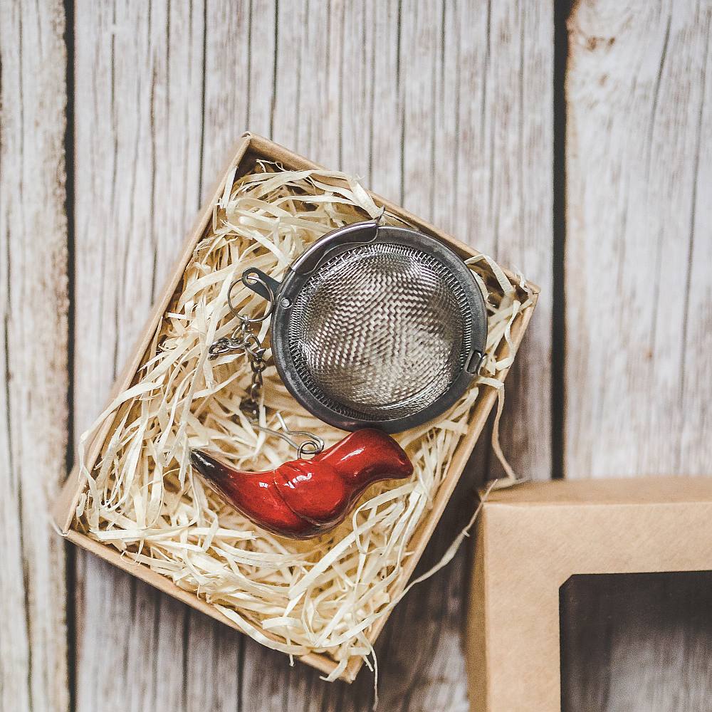 Tea infuser with ceramic red bird hanging from the chain. Packed in a paper gift box.