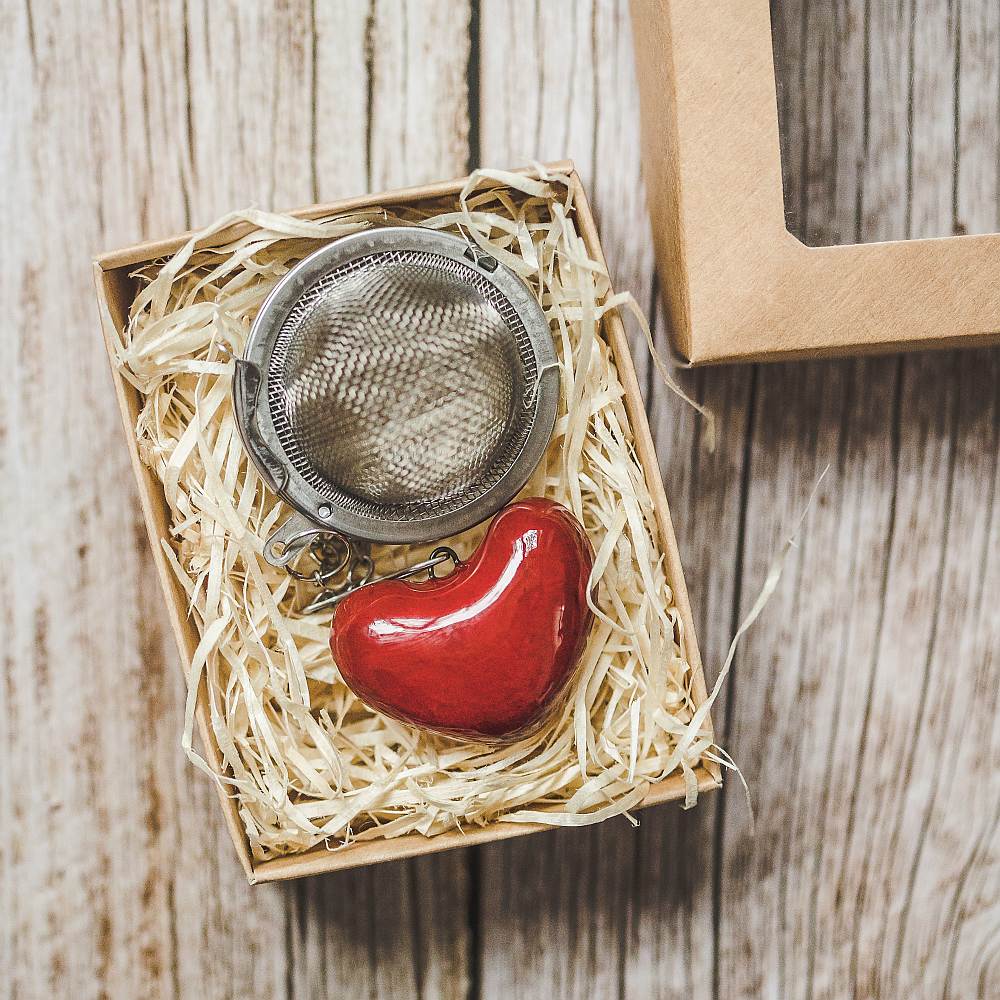 Tea infuser with ceramic red heart hanging from the chain. Packed in a paper gift box.