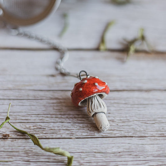 Tea infuser with red mushroom hanging from the chain.
