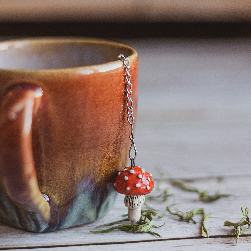 Tea infuser with red mushroom hanging from the chain.