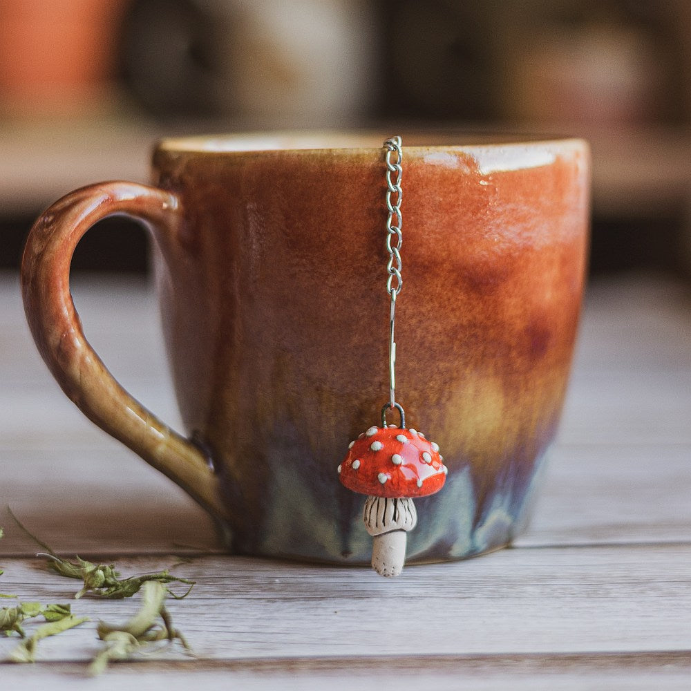Tea infuser with red mushroom hanging from the chain.