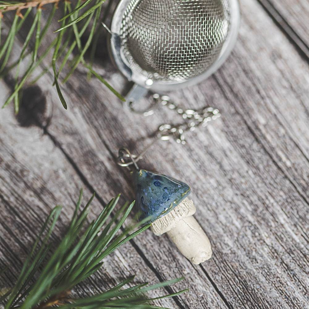 Tea infuser with ceramic swamp blue mushroom hanging from the chain.