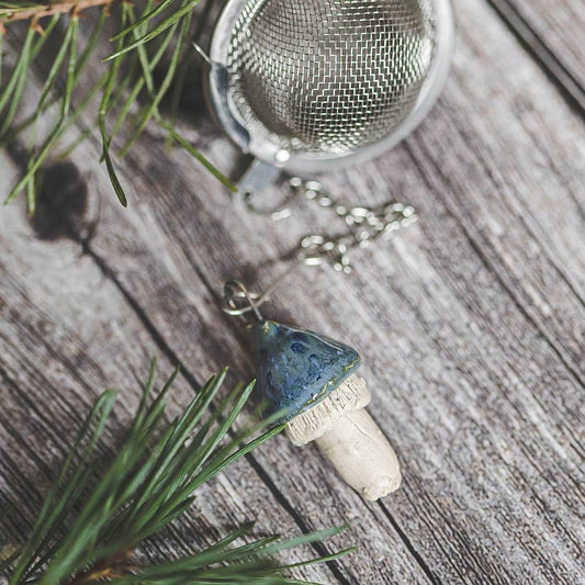 Tea infuser with ceramic swamp blue mushroom hanging from the chain.