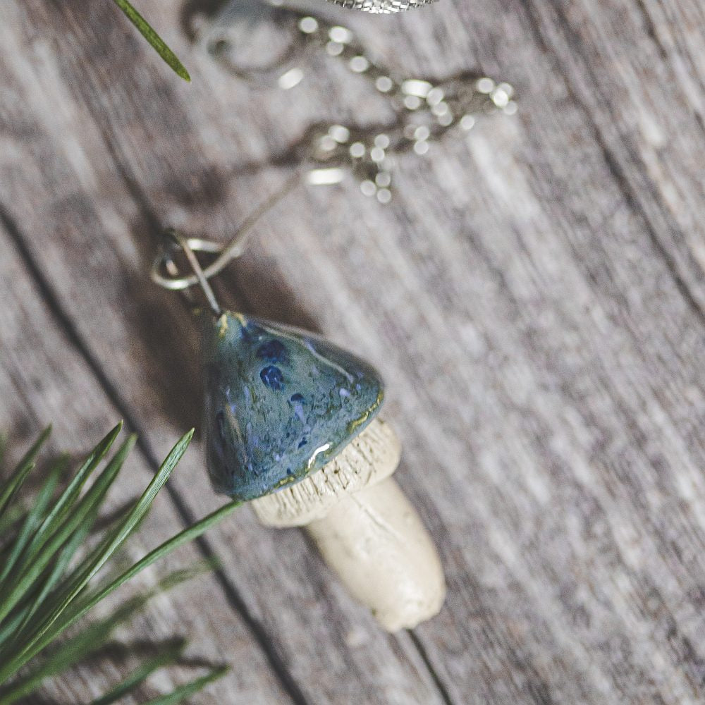 Tea infuser with ceramic swamp blue mushroom hanging from the chain.