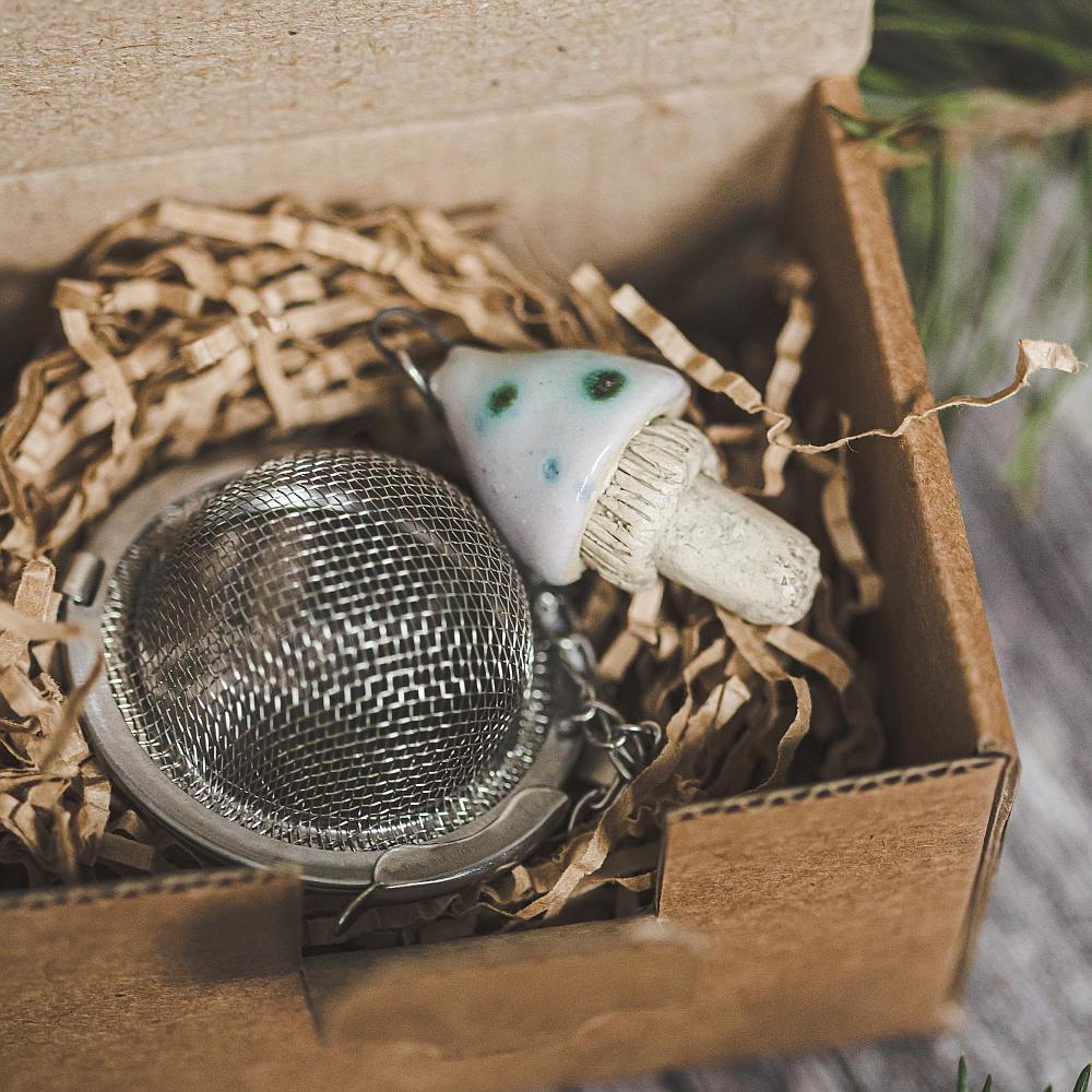 Tea infuser with ceramic swamp mushroom hanging from the chain. Packed in a paper gift box.