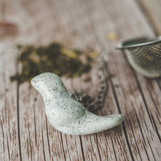 Tea infuser with ceramic white bird hanging from the chain.