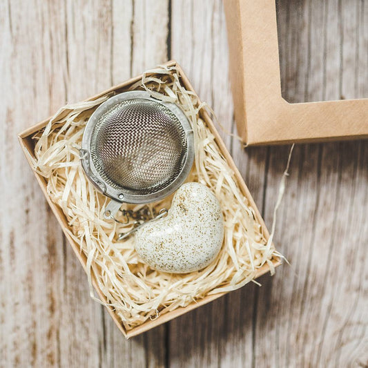 Tea infuser with ceramic white heart hanging from the chain. Packed in a paper gift box.
