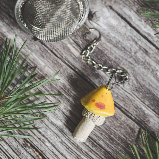 Tea infuser with ceramic yellow dotted mushroom hanging from the chain.