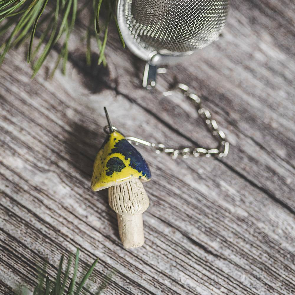 Tea infuser with ceramic yellow spotted mushroom hanging from the chain.