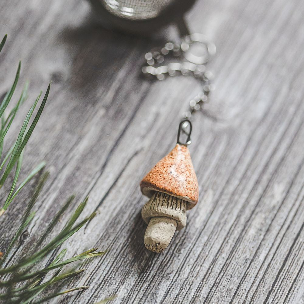 Tea infuser with ceramic yellowish mushroom hanging from the chain.