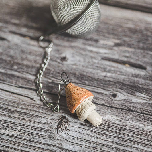 Tea infuser with ceramic yellowish mushroom hanging from the chain.