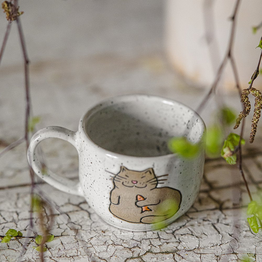 Handmade white ceramic mug with a glossy glaze, featuring an unglazed cat design on the side.