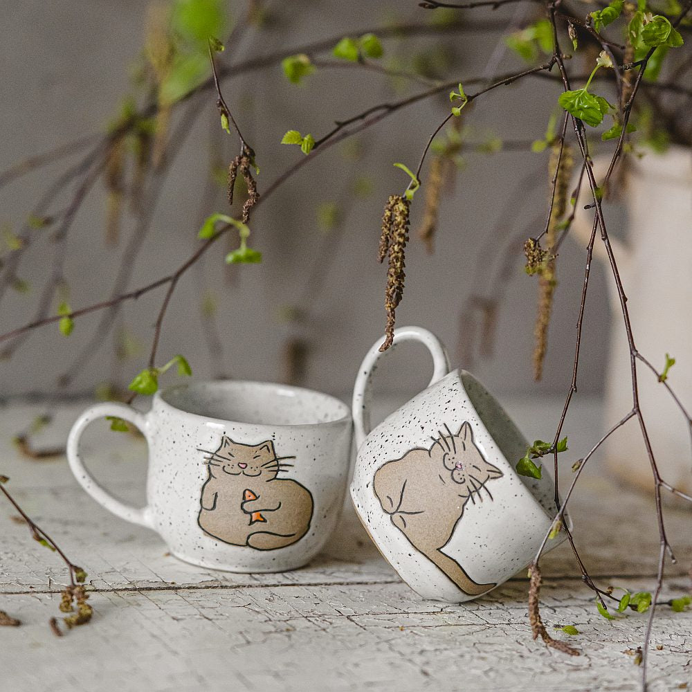 Handmade white ceramic mug with a glossy glaze, featuring an unglazed cat design on the side.