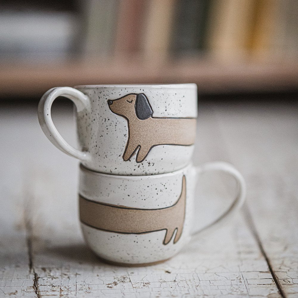 Handmade white ceramic mug with a matte glaze, featuring an unglazed dog design on the side.