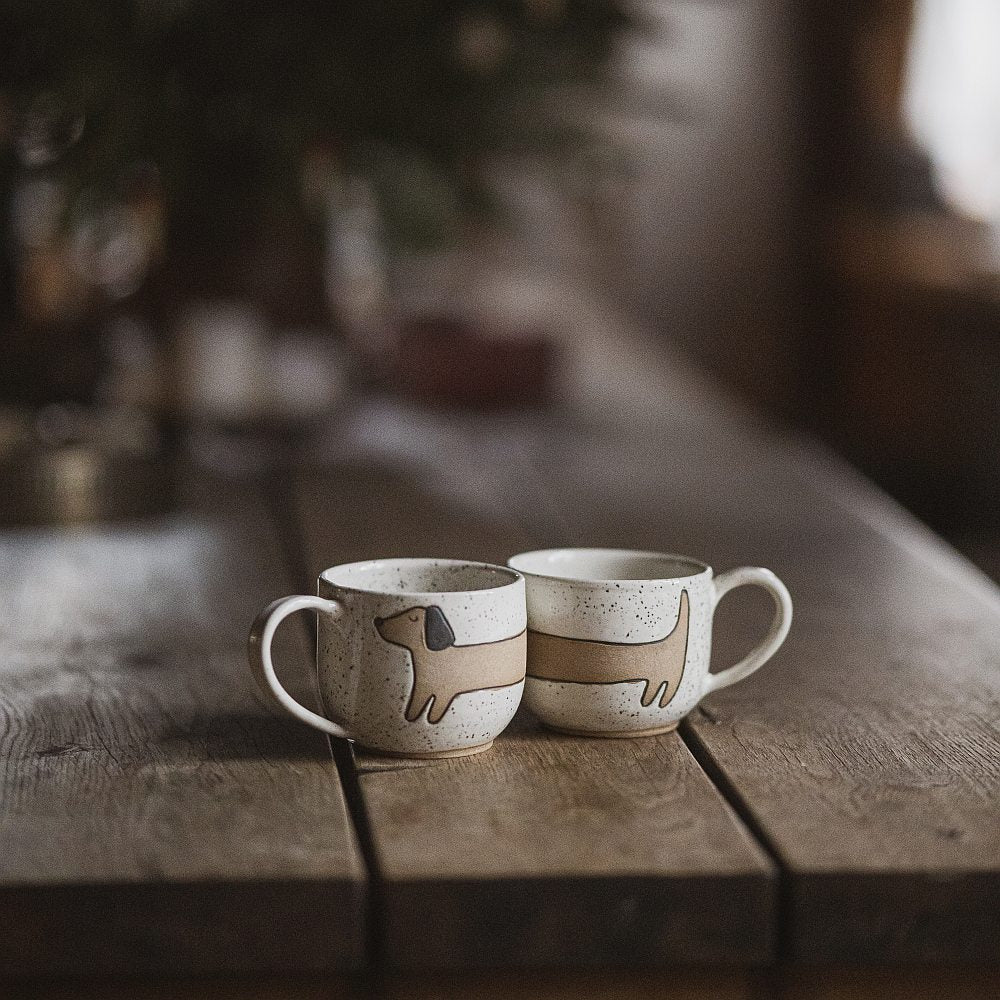 Handmade white ceramic mug with a matte glaze, featuring an unglazed dog design on the side.