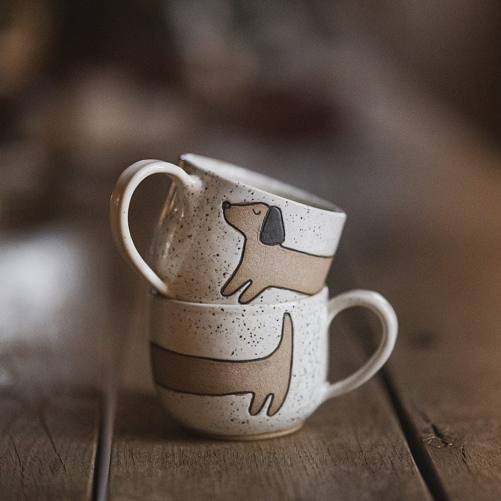 Handmade white ceramic mug with a matte glaze, featuring an unglazed dog design on the side.