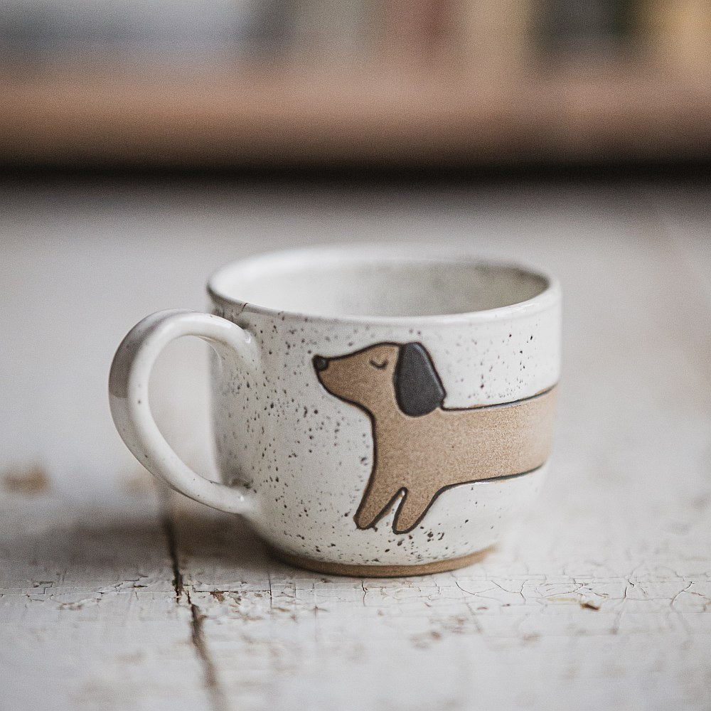 Handmade white ceramic mug with a matte glaze, featuring an unglazed dog design on the side.