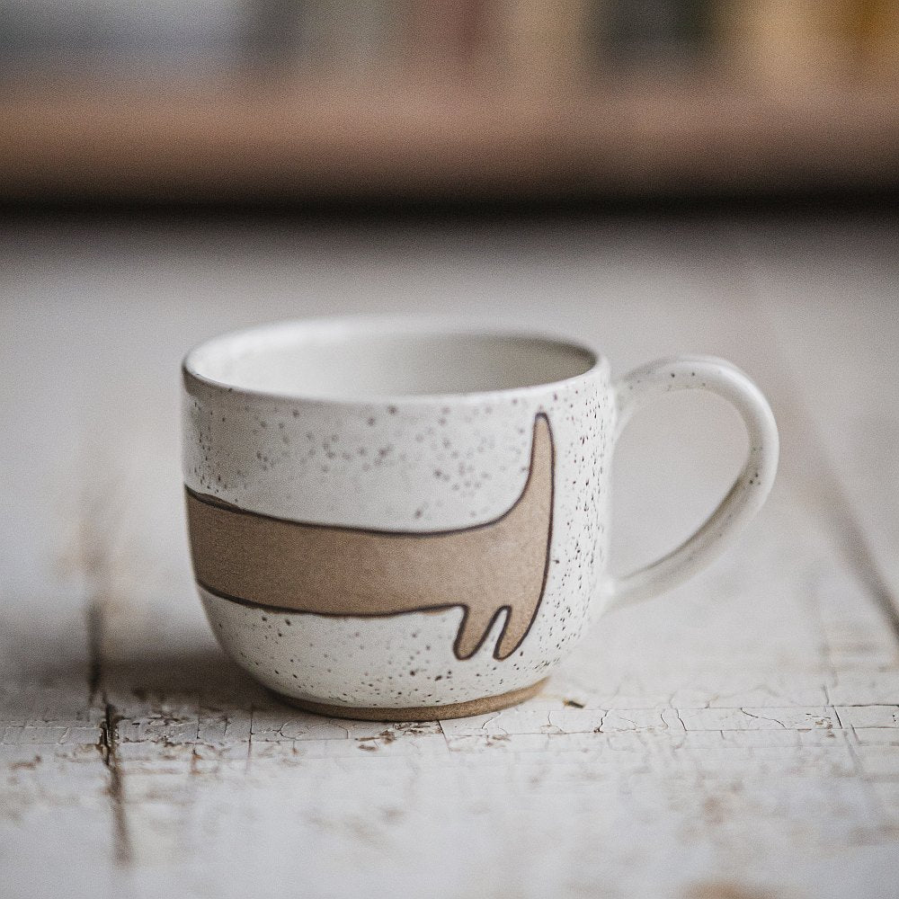 Handmade white ceramic mug with a matte glaze, featuring an unglazed dog design on the side.