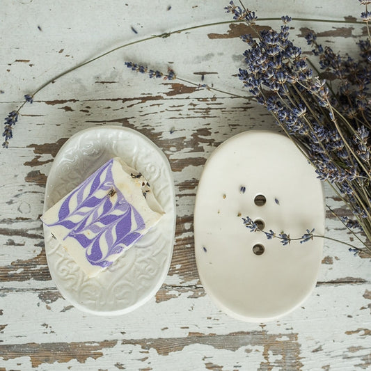 Handmade ceramic oval soap dish. Crafted from white clay and finished with a glossy white glaze. Designed with drainage holes, a concave shape, and four little feet.