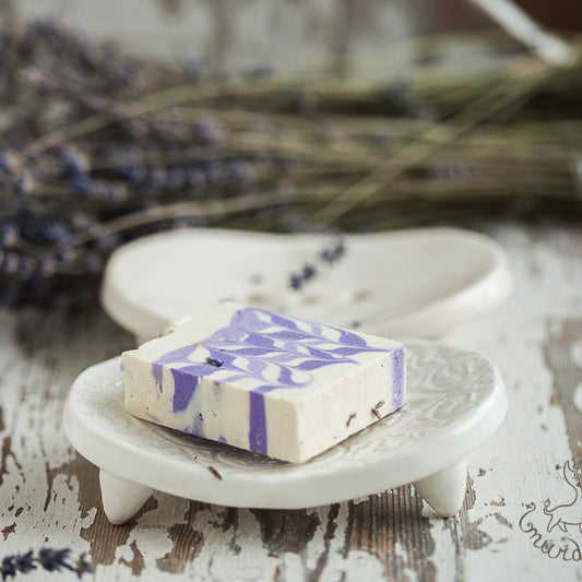 Handmade ceramic oval soap dish. Crafted from white clay and finished with a glossy white glaze. Designed with drainage holes, a concave shape, and four little feet.