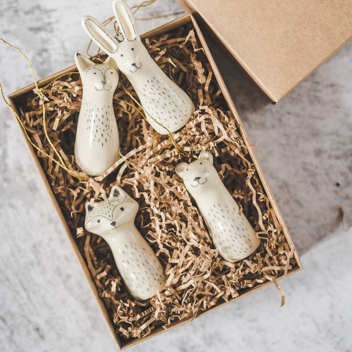 Christmas tree wild animals decoration set of four. Fox, bear, raccoon, hare ceramic ornaments hanging from a gold string.