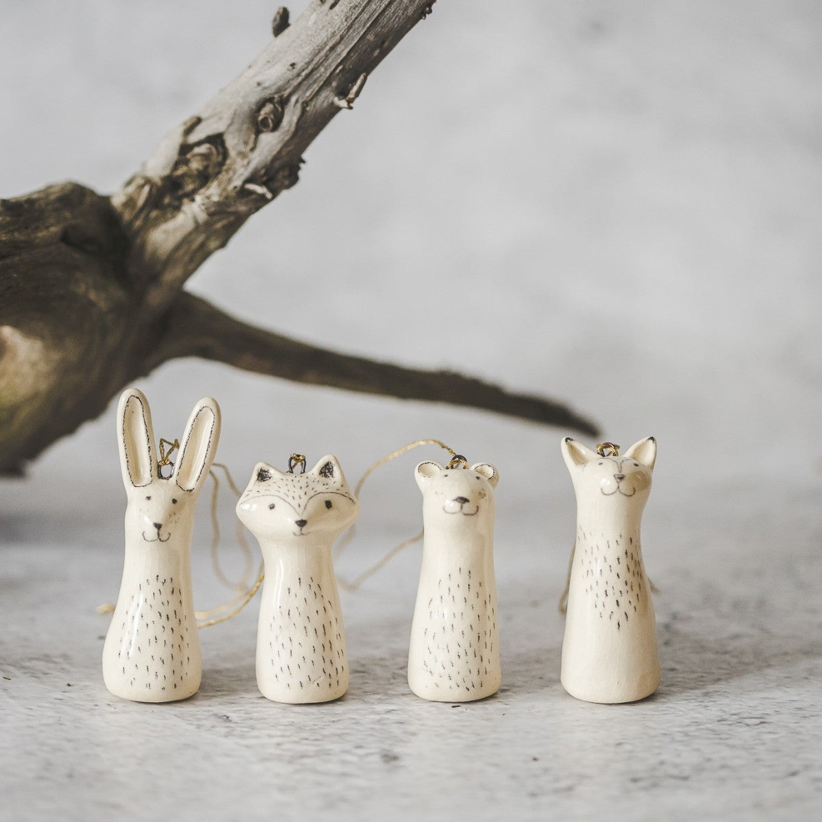 Christmas tree wild animals decoration set of four. Fox, bear, raccoon, hare ceramic ornaments hanging from a gold string.