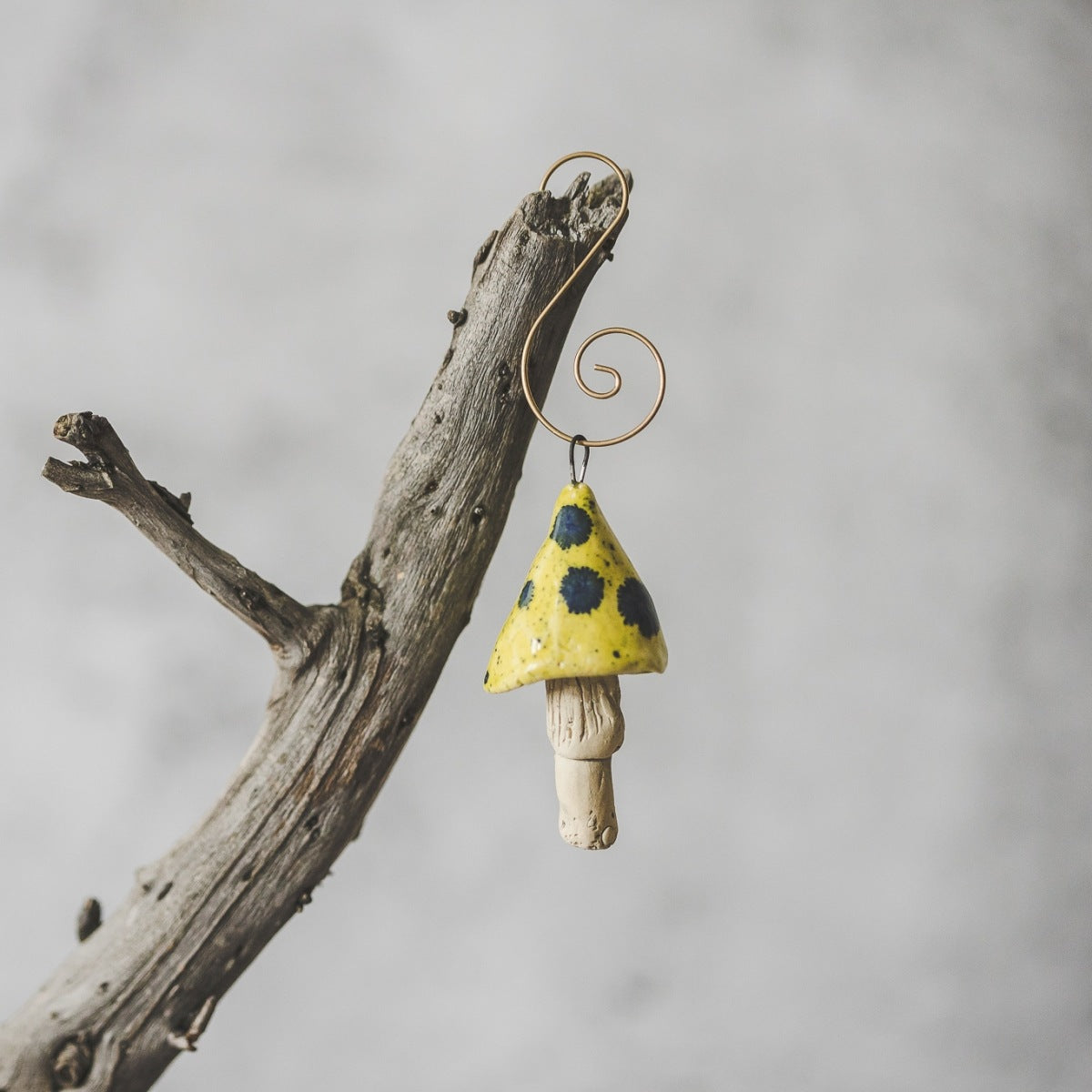 Yellow mushroom with blue spots. Ceramic ornament hanging on a branch of Christmas tree.