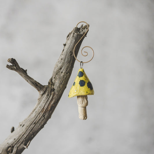 Yellow mushroom with blue spots. Ceramic ornament hanging on a branch of Christmas tree.