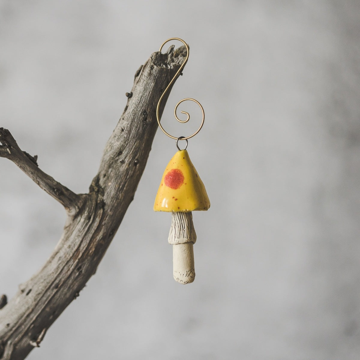 Yellow mushroom with red dots. Ceramic ornament hanging on a branch of Christmas tree.