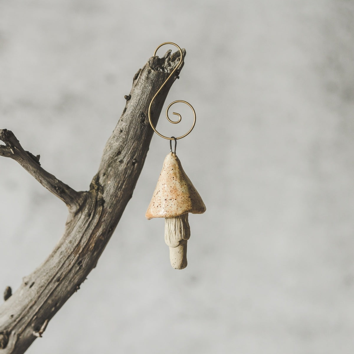 Ceramic yellowish swamp mushroom ornament hanging on a branch of Christmas tree.